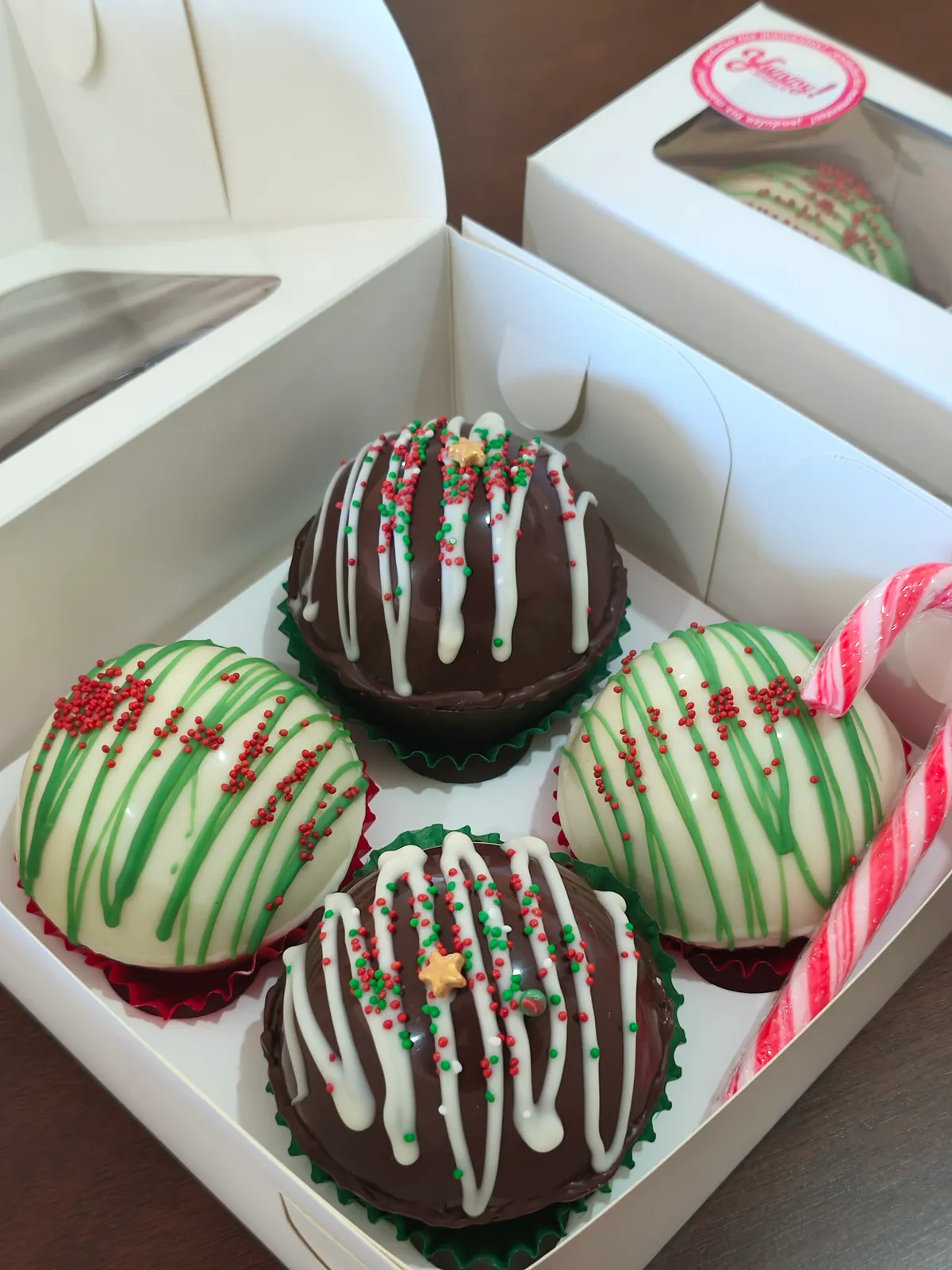 Cajas de Yummy con bombones de chocolate caliente decorados con grageas rojas y verdes y un bastón de caramelo