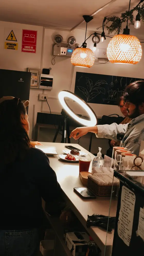 Dos personas atendidas en la barra de Yummy al caer la noche, con las lámparas colgantes encendidas