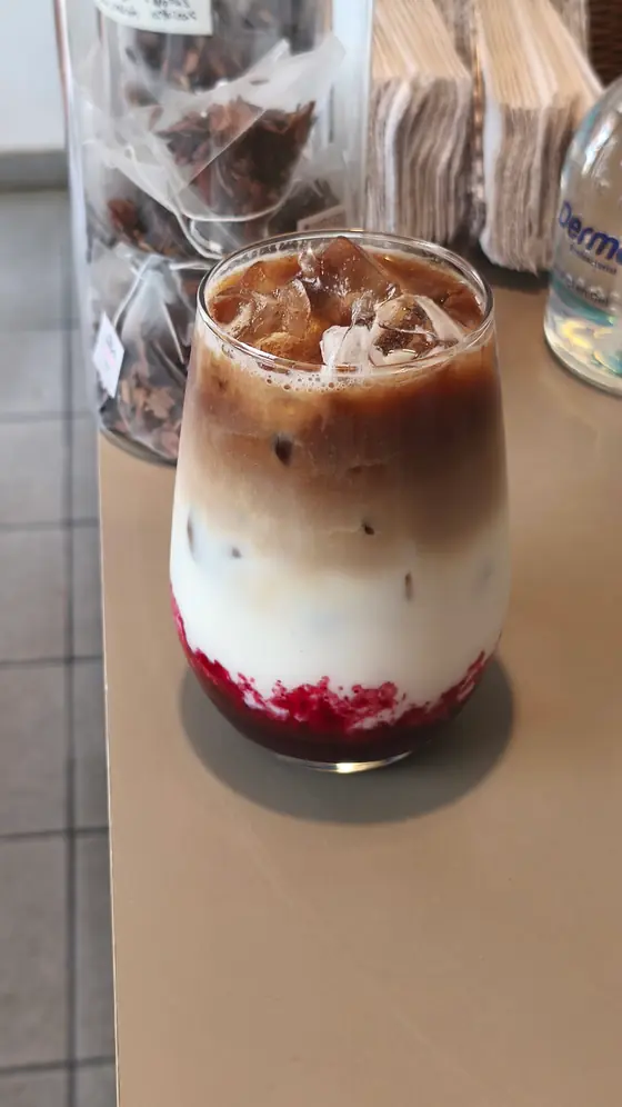 Berries cold brew latte servido en vaso de vidrio, con la capa de frutos rojos al fondo y el cold brew sobre la leche
