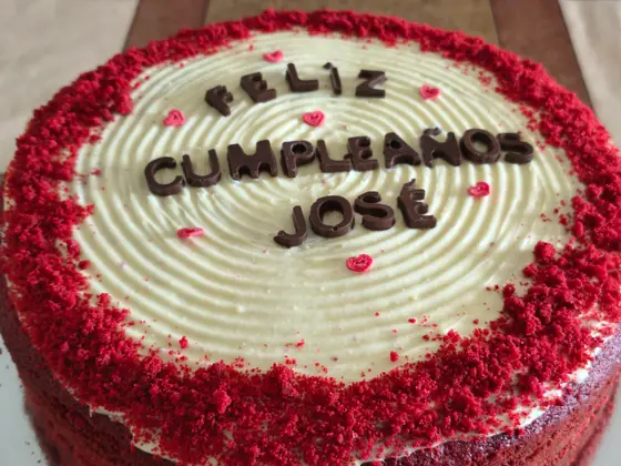Torta de cumpleaños personalizada con borde de red velvet y saludo escrito en chocolate